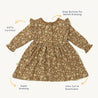 Flat-laid mustard-colored Organic Ruffle Dress - Wildflower from Makemake Organics with floral print, featuring long sleeves, snap buttons for easy dressing, and labeled as GOTS certified, super stretchy, and ultra
