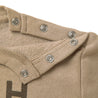 Close-up of a beige jacket collar from Organic Baby with multiple silver snap buttons, detailed stitching visible, and a fuzzy inner lining.