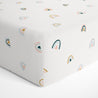 Close-up of a Makemake Organics crib fitted sheet with pillowcase featuring a colorful rainbow pattern on a white background.