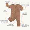 An image of a beige Organic 2-Way Zip Romper - Sparkle baby onesie with star patterns, featuring labels such as gots certified, fabric neck protector, ultra soft, 2-way zipper, and foldover mitts for sizes up to 12m from Organic Baby.
