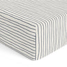 A close-up image of the corner of a mattress with an Organic Cotton Sheet Set - Cobi Blue Stripes from Makemake Organics featuring evenly spaced thin dark blue horizontal stripes.