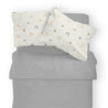 Top view of a neatly made bed with gray blankets and two pillows featuring the Makemake Organics Organic Cotton Toddler Pillowcase - Rainbow, set against a plain background.