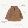 A quilted, caramel-colored children’s jacket made from 100% merino wool by Organic Kids, featuring a front zipper, kangaroo pockets, and labeled with icons emphasizing its breath.